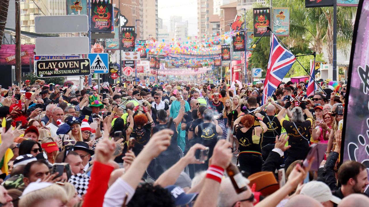Packed street in costumes under bunting in Rincón de Loix