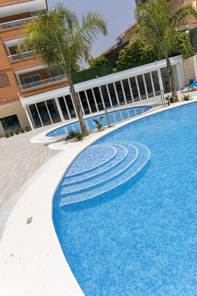 Levante Lux: Pool steps, Curved pool with palms and a shaded terrace behind