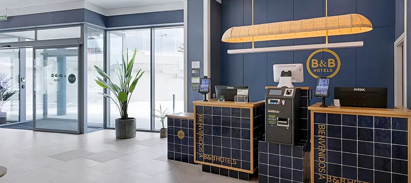 B&B Finestrat: Reception, Tiled reception desk with check-in kiosks beside the glass entrance