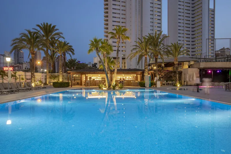 BCL Levante Club: Pool at dusk, Lit pool with palms and loungers below tower blocks