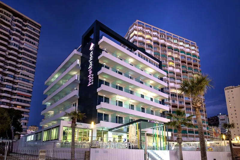 Brisa: The hotel at night, Lit hotel building among tall towers at dusk