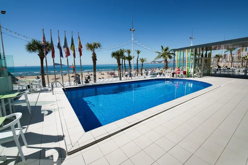 Brisa: Rooftop pool, Pool terrace with flags and the beach beyond