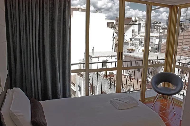 Casa Don Juan: Room with balcony, Bed beside glass doors onto a balcony over rooftops