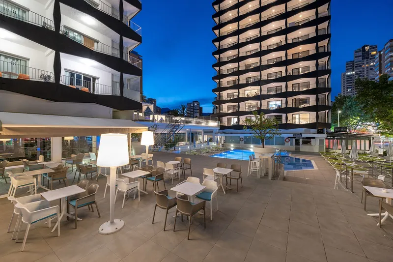 Belroy: Pool terrace at dusk, Terrace tables and lit pool below the hotel tower
