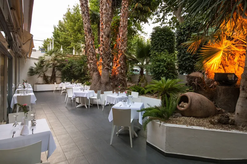 Belroy: Garden restaurant, Outdoor tables set with white cloths among palms
