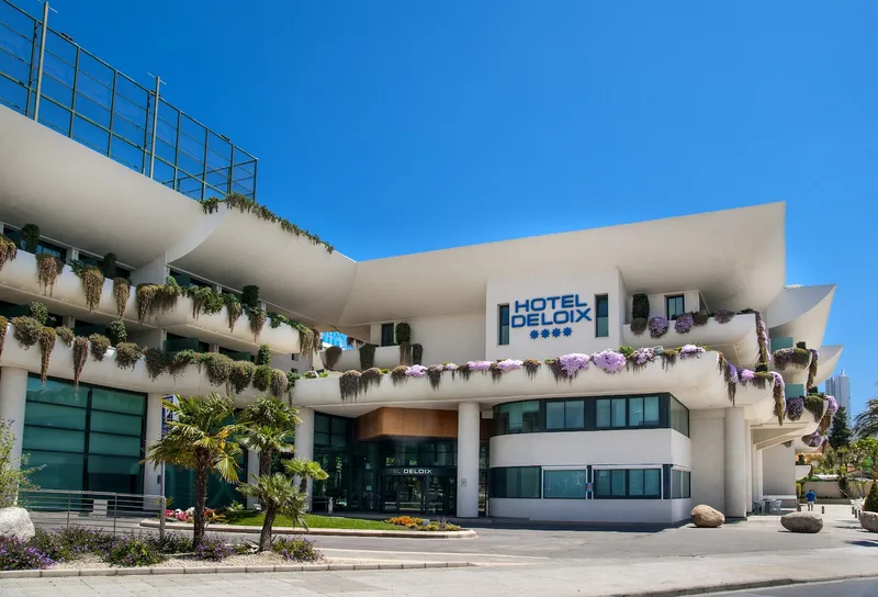 Deloix: Hotel entrance, Curved white facade with hanging plants and the Hotel Deloix sign