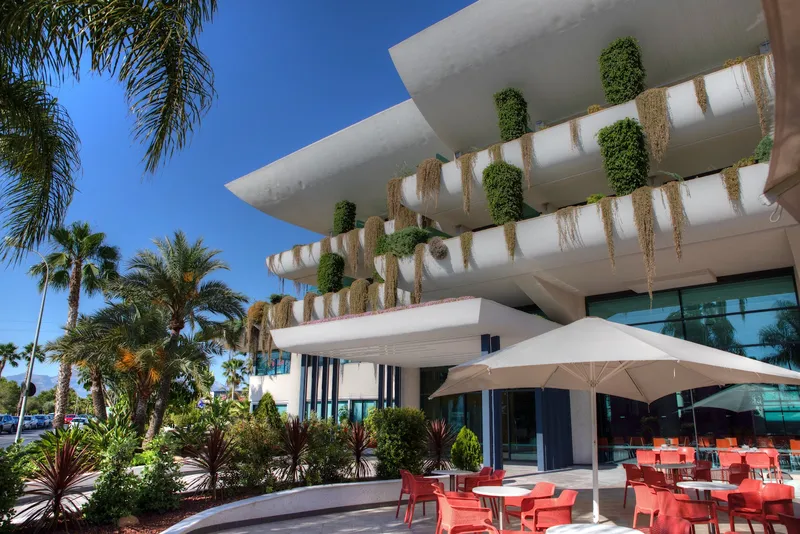 Deloix: Outdoor terrace, Terrace with red chairs and parasols below planted balconies