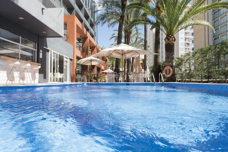 El Palmeral: Pool terrace, Pool with parasols and tables under tall palm trees