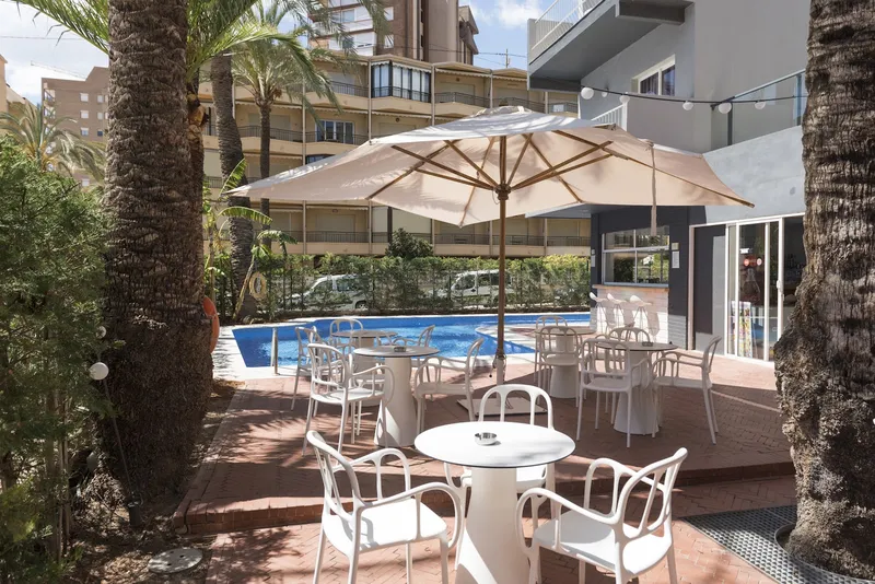 El Palmeral: Garden terrace, White tables and chairs under parasols by the pool