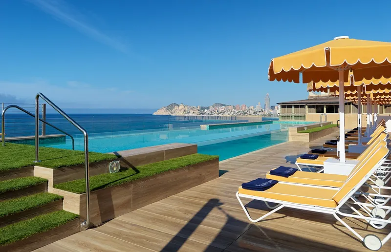 Porto Poniente: Rooftop pool, Infinity pool and yellow loungers looking across the bay