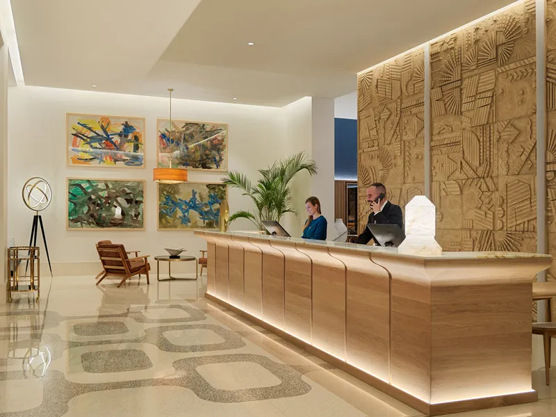 Porto Poniente: Reception, Long wooden reception desk with artwork behind