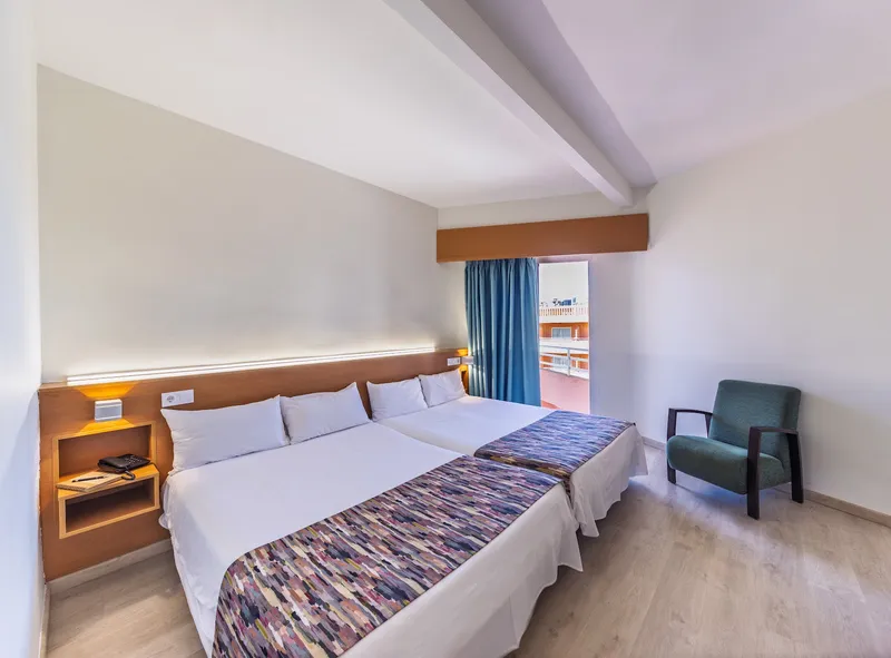 Medsur Alone: Twin room, Two beds, armchair and window with blue curtains