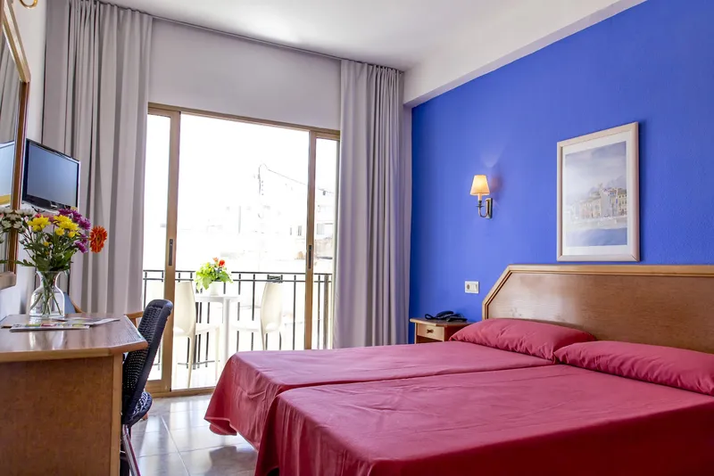 Colón: Twin room, Twin beds in red covers with balcony doors and blue feature wall