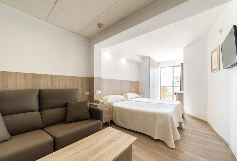 Montemar: Twin room, Twin room with brown sofa and wall-mounted TV