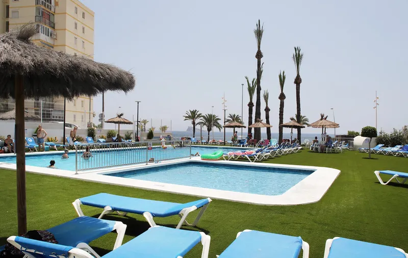 Poseidón Playa: Pool, Pool and lawn with loungers and sea beyond