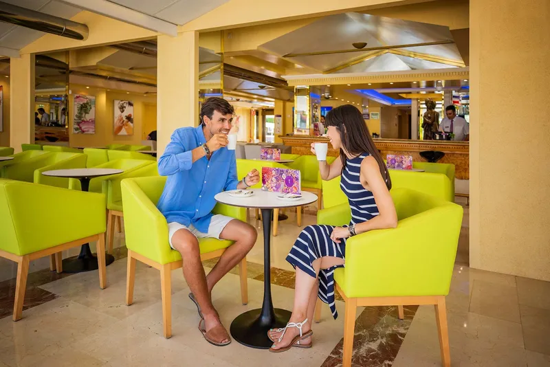 Venus: Café-bar, Café-bar with lime green armchairs and round tables
