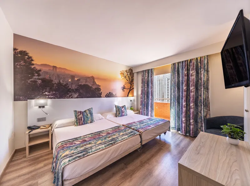 Tropic Relax: Twin room, Twin beds below a large sunset mural with balcony doors