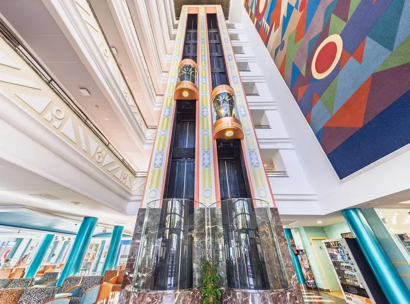 Tropic Relax: Atrium, Glass lifts rising through a central atrium with a colourful mural