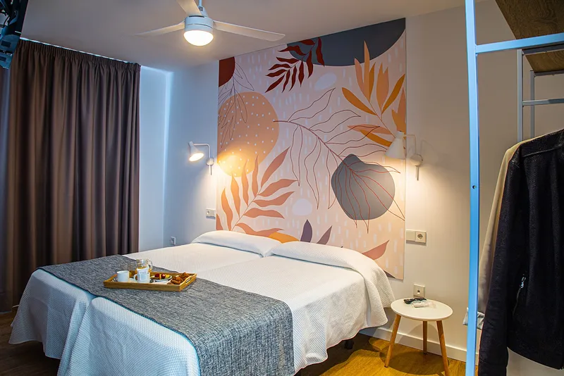 Internacional: Double room, Twin beds pushed together under a leaf-print mural