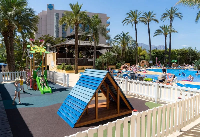 Flamingo Oasis: Kids play area, Fenced playground beside the pool and palms