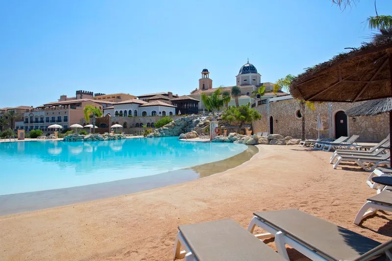 Villaitana: Lagoon pool, Lagoon-style pool with a sandy edge, loungers and a thatched parasol