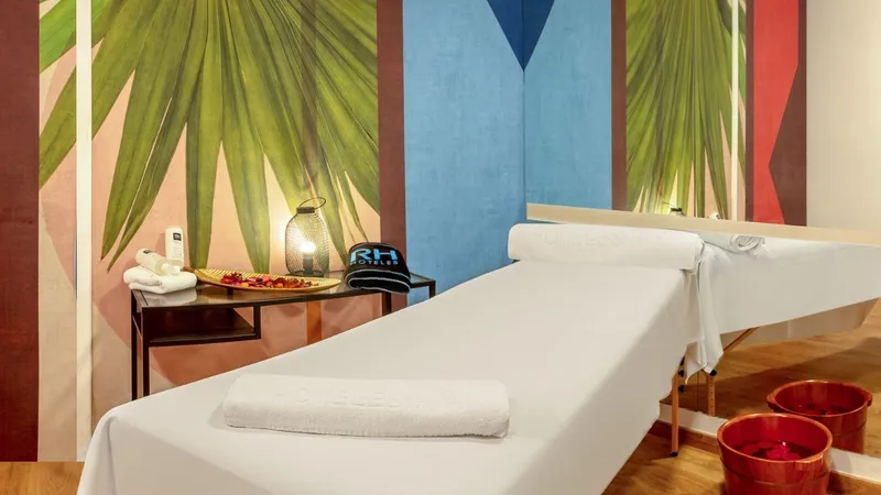 RH Victoria: Treatment room, Massage bed with towels and painted palm leaf wall