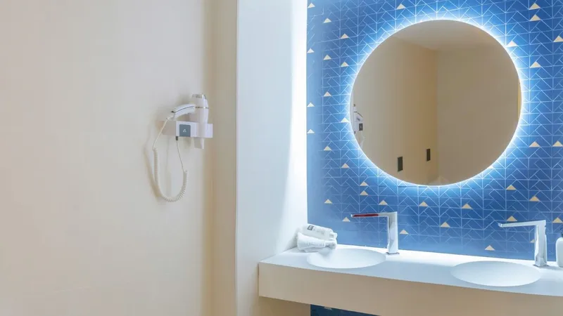 RH Victoria: Bathroom, Twin basins under a round lit mirror on blue tiles