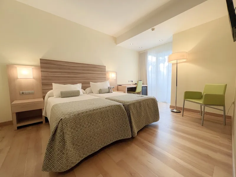 Riviera: Twin room, Twin beds, armchair and floor lamp by the window