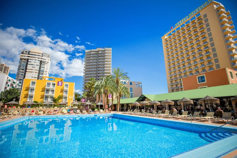 Pueblo: Pool, Pool and loungers below the hotel tower and palm trees