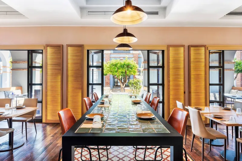 The Level: Restaurant, Long communal table and leather chairs below pendant lamps