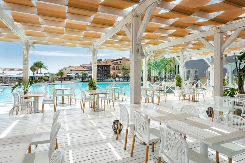 The Level: Poolside restaurant, White tables under a pergola beside the pool